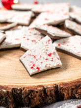 Load image into Gallery viewer, Pieces of peppermint bark on the end of a round log