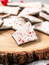 Load image into Gallery viewer, Pieces of peppermint bark on the end of a round log
